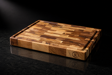 Premium end-grain maple cutting board shot like a luxury product with beaded moisture and dramatic light