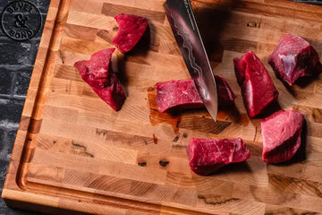 A well-used Bevel & Bond end-grain maple cutting board mid-use with knife, herbs, and lemon
