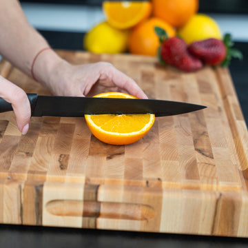 Cleaning a wooden cutting board by hand at the sink