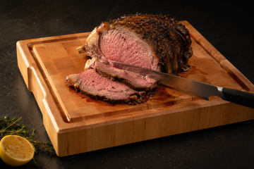 Carving a roast on an end-grain maple board with juices collecting in the juice groove