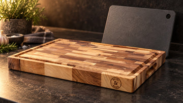 A thin grey paper composite cutting board leaning behind a thick Bevel & Bond end grain maple cutting board