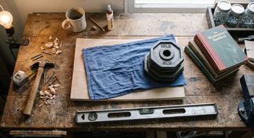 Warped wooden cutting board clamped flat under weights with a damp cloth