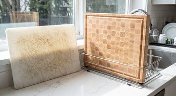 Scored plastic cutting board beside a clean maple board drying upright
